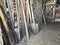 Vintage agricultural tools stand in a row in a wooden barn: rakes, hoes, pitchfork, shovels and more