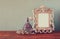 Vintage antigue perfume bottles with old picture frame, on wooden table. retro filtered image