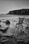 Vintage antique chair tucked into the water of an Irish beach surrounded by rocks and cliffs. long exposure with traces of water.