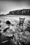 Vintage antique chair tucked into the water of an Irish beach surrounded by rocks and cliffs. long exposure with traces of water.