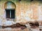 A vintage arched window on the grungy decayed brick wall of an old house in