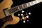 Vintage archtop guitar in natural maple close-up from above on black background with various picks