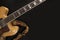 Vintage archtop guitar in natural maple close-up with colored strap from above on black background