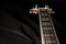 Vintage archtop guitar in natural maple close-up high angle view on black background, rosewood fingerboard with frets and fret