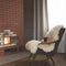 A vintage armchair covered with white furskin for pleasant reading and relaxation near the fireplace in dark interior.