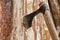 Vintage ax with a narrow blade stuck in a vertical wooden panel close-up