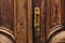 Vintage background. Brass-made old handle with Elements of an carved wooden door decorated with massive wooden