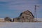 Vintage barn, bins and windmill surrounded by snow under a pink sunset sky in Saskatchewan