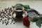 Vintage beautiful cup of hot coffee, bright red rose, green leaves, scattered coffee beans and dark chocolate bar on a wooden tabl