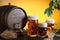 Vintage beer barrel with beer glasses on wooden table with wheat bunch, hop and barley