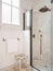 Vintage beige color bathroom with shower zone, window, towel and wooden stool