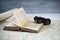 Vintage binoculars and antique open book on the old map