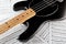 Vintage black bass guitar on music sheets background