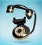 Vintage black corded telephone flying in air on light blue background