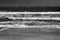 Vintage black and white grainy film concept. Seascape with empty sand beach and quiet waves