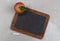 A vintage blank slate chalkboard with an apple on a grey mottled surface. Back to school concept with copy space