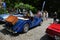 Vintage blue convertible parked on a cobblestone road surrounded by people