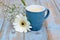 Vintage blue cup of coffee on a wooden background with white Gerbera daisy decoration