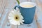 Vintage blue cup of coffee on a wooden background with white Gerbera daisy decoration