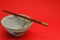 Vintage blue Rice bowl with sakura flowers and traditional bamboo chopsticks on bright red background.