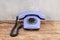 Vintage blue rotary dial telephone on wooden table in front gray concrete background