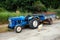 Vintage Blue Tractor and Trailer and a White Dog