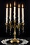 Vintage brass candelabra of five burning candles with dripping wax on a black background vertical background. photo