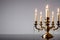 Vintage brass candelabra of five burning candles with dripping wax on a black background vertical background. photo