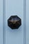 Vintage brass doorknob with worn black paint on light blue wooden door