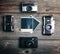 Vintage cameras around empty retro photograph on wooden background