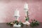 Vintage candlesticks with burning candles, roses and eucalyptus on table