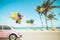 Vintage car with colorful balloon on tropical beach