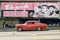Vintage car next to a poster supporting the Cuban Revolution in