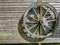 A vintage cart wheel on an unpainted wooden garden screen