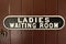 A vintage cast iron ladies waiting room sign.