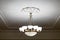 Vintage chandelier hanging under white ceiling with stucco moldings