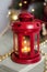 Vintage Christmas Lantern Red with burning Candles. Cozy christmas decorations with golden beads, balls. Christmas tree on