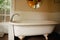 Vintage clawfoot cast iron bathtub in white and creme bathroom with wall decor and round mirror