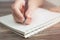 Vintage close up of female hand writing taking notes with pen in blank spiral notebook.