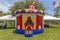 Vintage colorful patriotic small gazebo bounce house inflated in front of two tents selling souvenirs for all who visit the