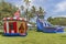 Vintage colorful small gazebo bounce house inflated next to a large blue twin falls inflated kids slip and slide