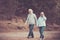 Vintage colors orange tone couple of caucasian senior man and woman walking together in the park having fun - life forever with