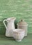 Vintage cookware - enameled jar, pitcher and white ceramic bowl on a green wooden surface