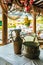 Vintage copper jug and bowler pot on a table with a colored tablecloth. Hanging bunch of ripe bananas and a local village in the