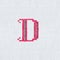 Vintage cross-stitch letter D on linen fabric