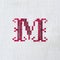 Vintage cross-stitch letter M on linen fabric