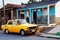 vintage Cuban car parked in front of tropical home in rural Cuba