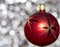 Vintage decorative christmas bauble in red color with large decorative stars  against a silver bokeh blurry star background