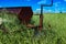 Vintage farming disc harrow in a field surrounded by tall grass with wind turbines