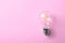 Vintage filament lamp bulb on pink , top view. Space for text